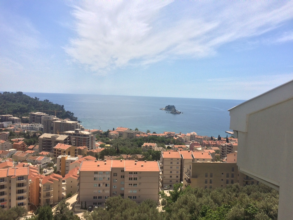 Panoramski pogled na more i grad Petrovac u Crnoj Gori iz prozora stana, pogled na stambenu četvrt i ostrvo u moru.