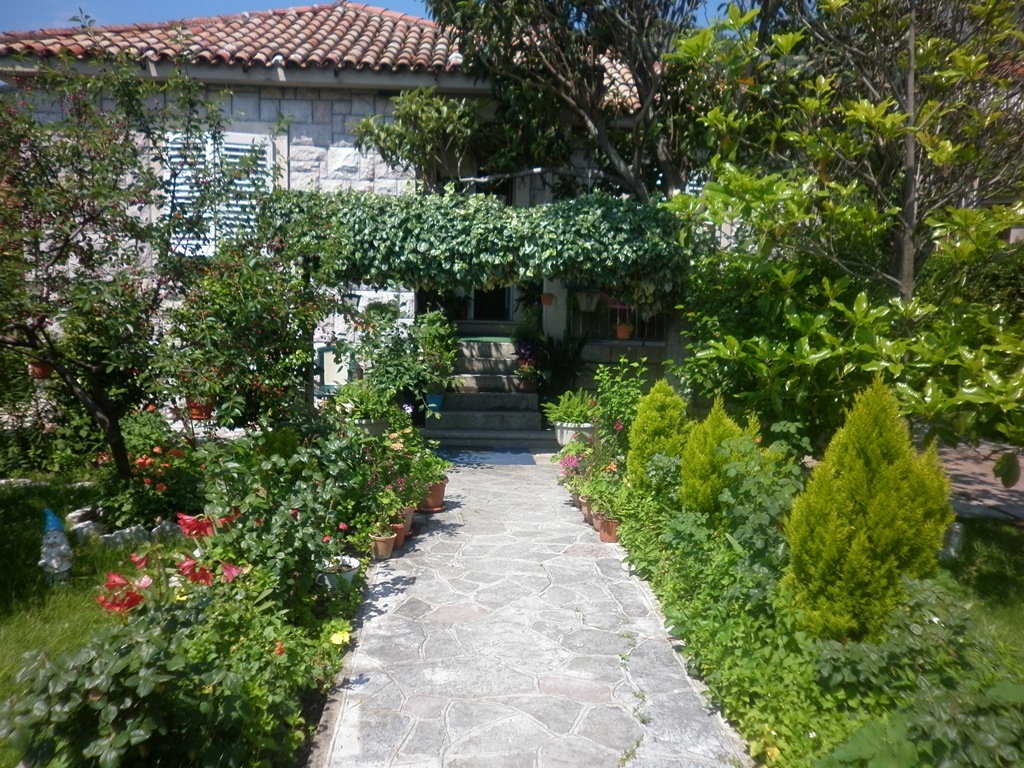 Steinhaus in Kamenari, Montenegro: Blick auf einen gemütlichen Garten mit gepflastertem Weg, Grünanlagen und Terrasse.