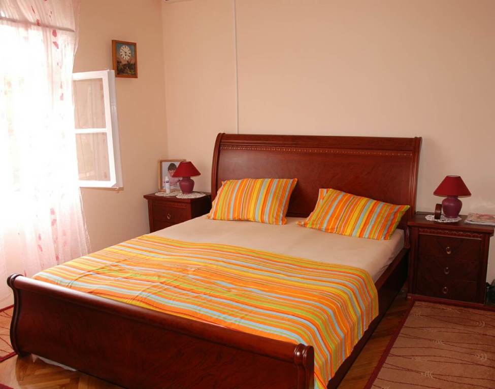 Gemütliches Schlafzimmer mit Doppelbett in einem Haus zum Verkauf, Kamenari, Montenegro: Holzmöbel und helles Interieur.