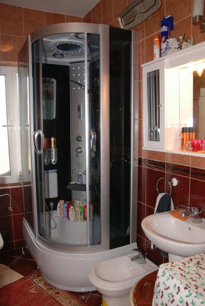 Badezimmer in einem Haus in Kamenari, Montenegro: Duschkabine mit Hydromassage, Waschbecken, Bidet und Fliesenverkleidung.