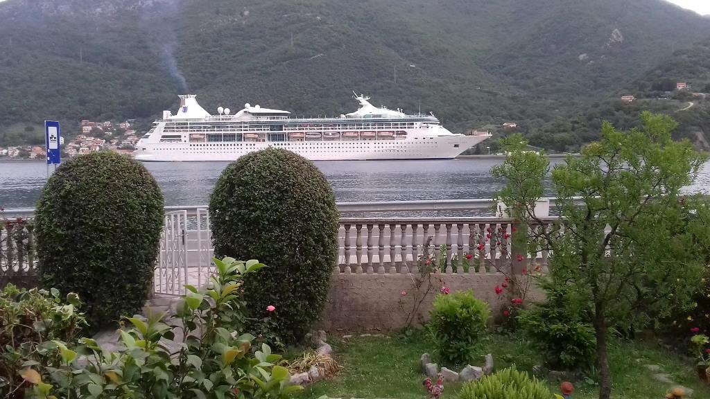 Meerblick und Kreuzfahrtschiff vom Garten des Hauses in Kamenari, Montenegro: gepflegtes Grundstück mit Zaun und Grünanlagen.