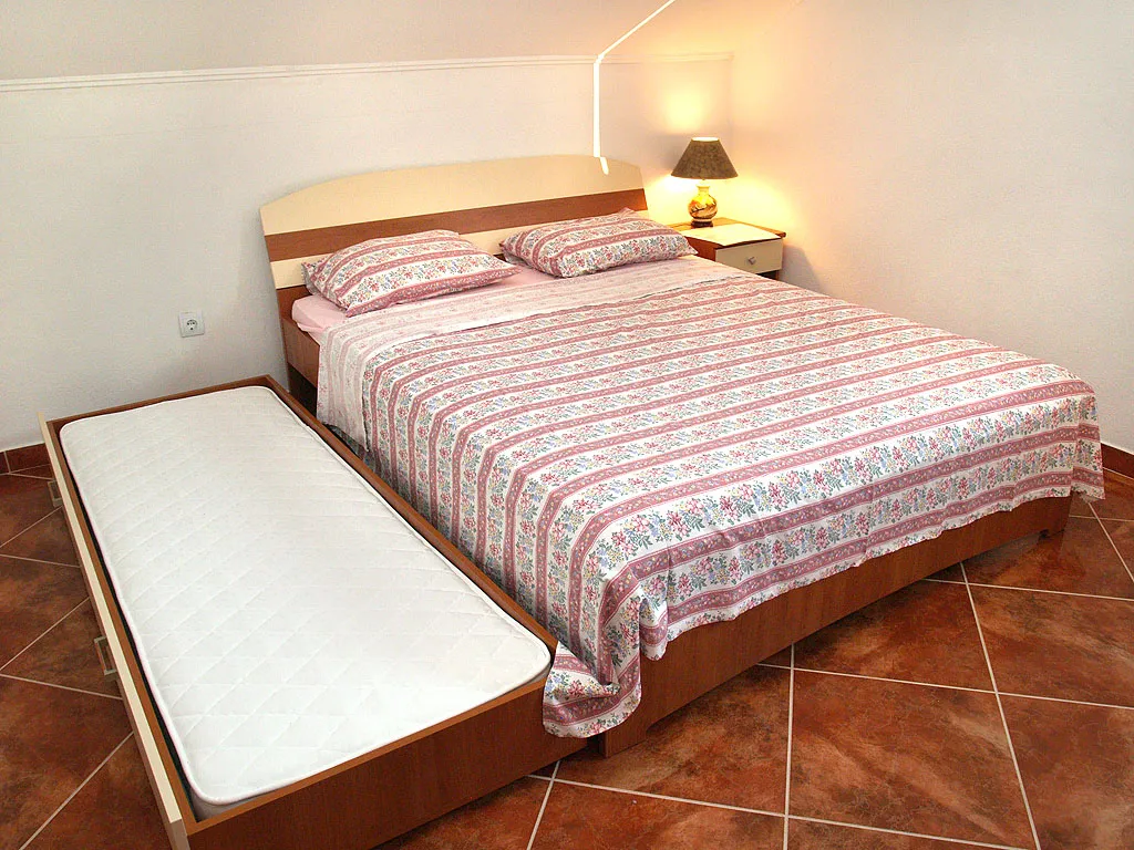 Bedroom with a double bed and pull-out bed in a villa in Stoliv, Montenegro: tiled floor, cozy lamp.