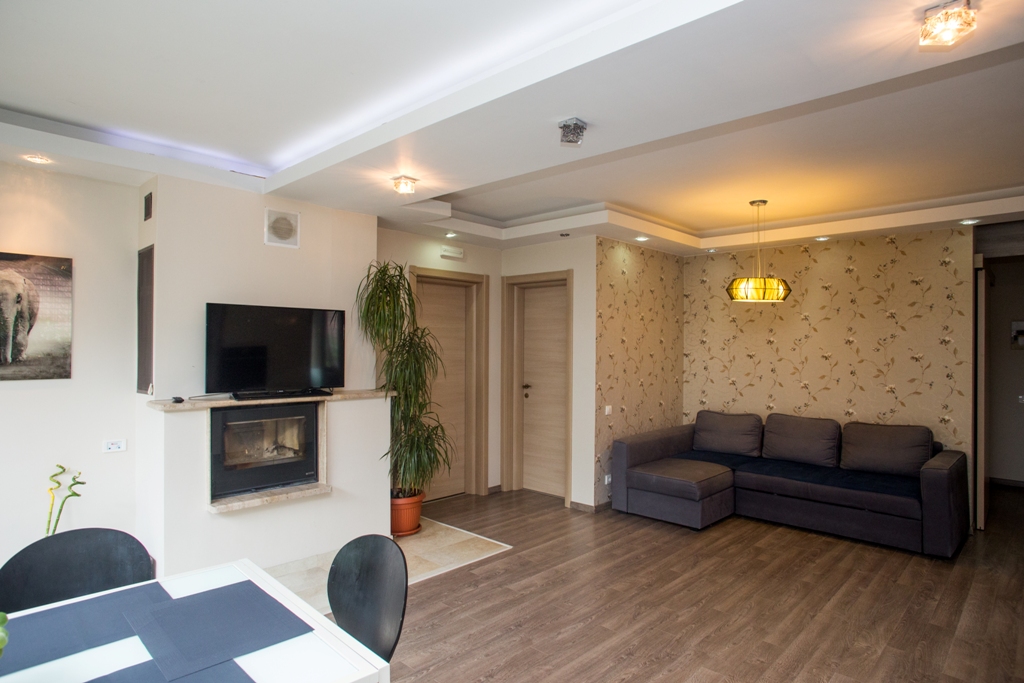 Wohnzimmer mit Kamin und grauem Sofa in einem Haus in Orahovac, Bucht von Kotor, Montenegro: modernes Interieur mit Dekor.
