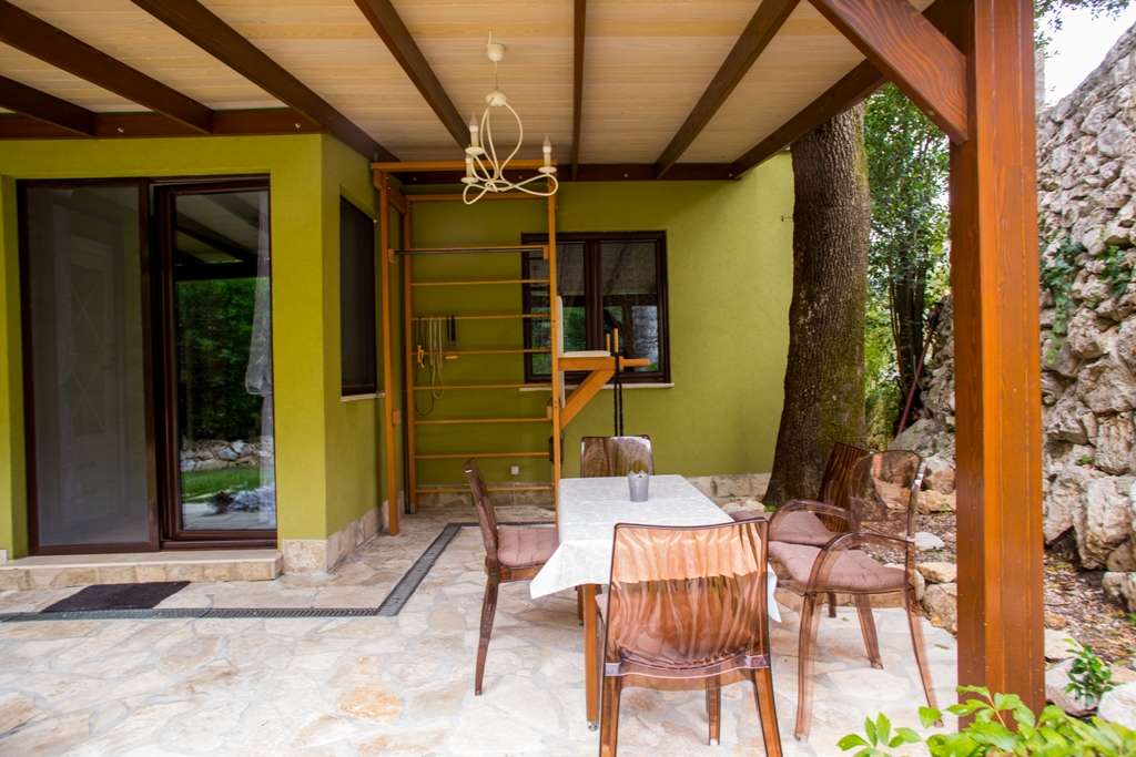 Überdachte Terrasse eines Hauses in Orahovac, Bucht von Kotor, Montenegro: Essbereich, Sprossenwand und Steinmauerwerk.