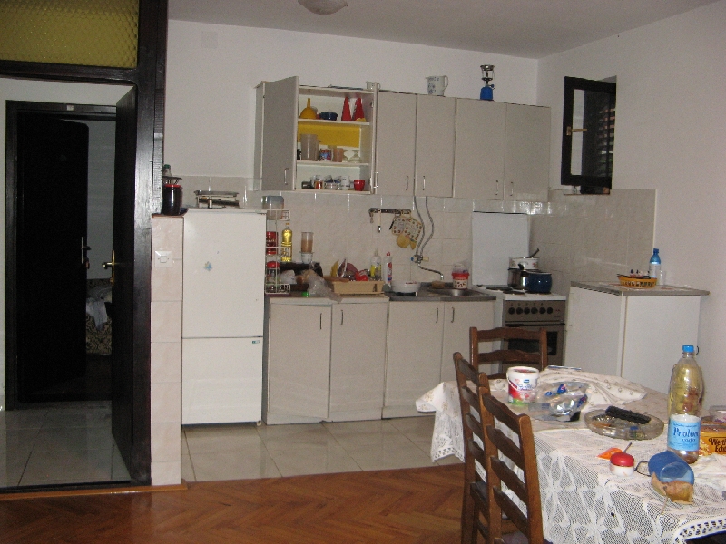 Cuisine dans une maison à Shushan, Monténégro : mobilier clair, table à manger, appareils électroménagers et parquet dans l’intérieur.