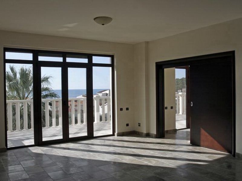 Panoramik pencereli ve deniz manzaralı aydınlık oturma odası, villa, Petrovac, Karadağ: taş zemin ve sürgülü kapılar.