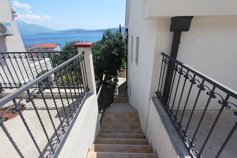 Treppe mit schmiedeeisernem Geländer und Meerblick am Haus in Baošići, Montenegro: Terrasse und geflieste Fassadenverkleidung.