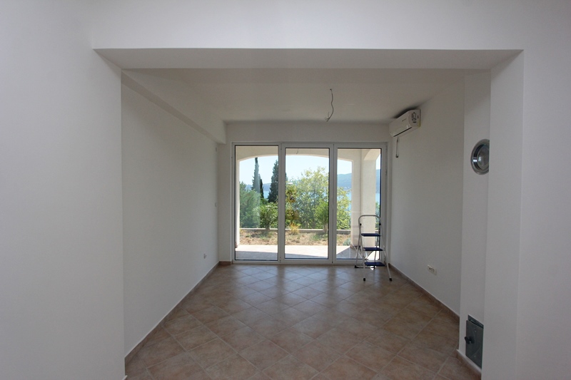 Helles Wohnzimmer mit Panoramafenstern und Meerblick in einem Haus, Baošići, Montenegro. Fliesenboden und weiße Wände.