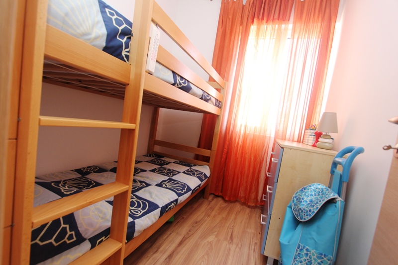 Kinderzimmer mit Etagenbett in einem Haus in Baošići, Montenegro: heller Raum mit Kommode und bunten Vorhängen.