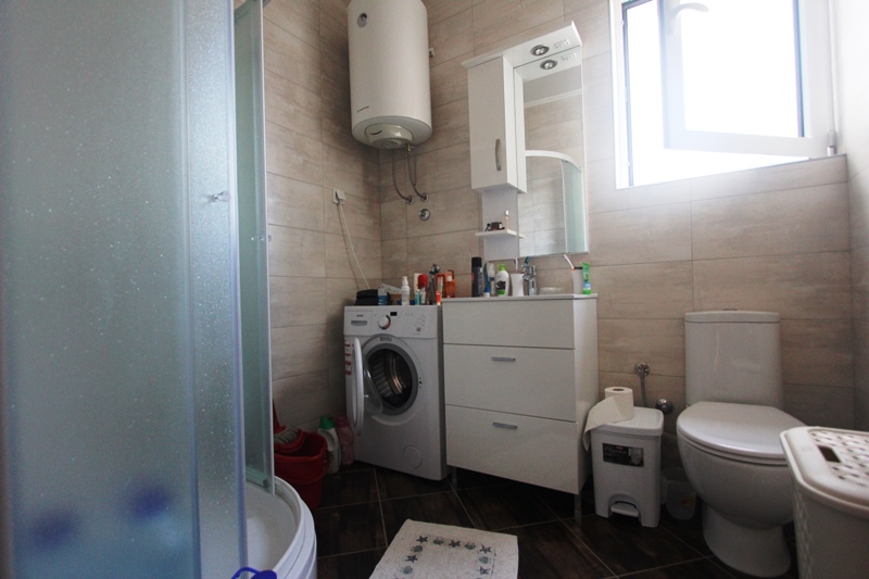 Badezimmer in einem Haus in Baošići, Montenegro: Duschkabine, Waschmaschine, Waschtisch mit Spiegel und Boiler.