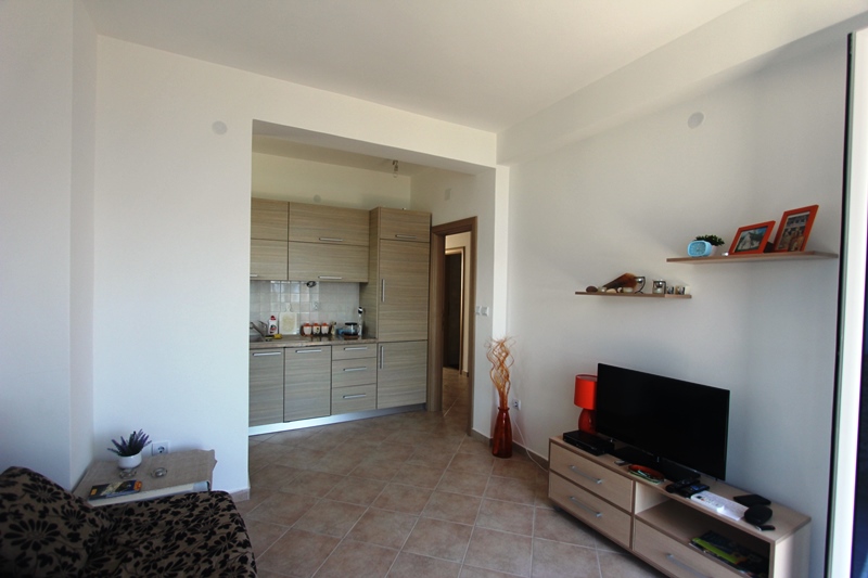 Wohnzimmer mit Küche in einem Haus in Baošići, Montenegro: helles Interieur, moderne Möbel, TV-Bereich und Fliesenboden.