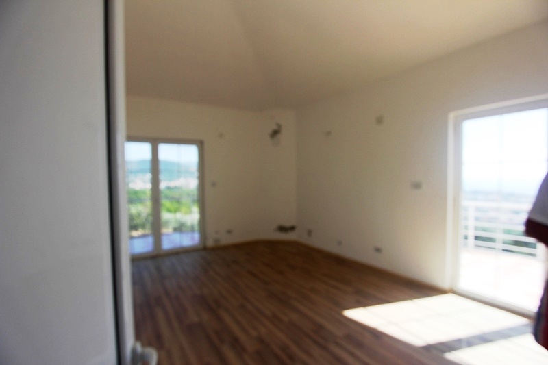 Bright living room with panoramic windows and parquet flooring in a villa in Dobra Voda, Montenegro. Mountain and terrace view.