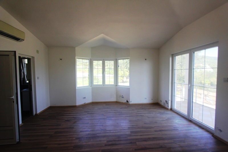 Bright living room with a bay window and access to the terrace in a villa, Dobri Vody, Montenegro: laminate flooring, panoramic windows, garden view.