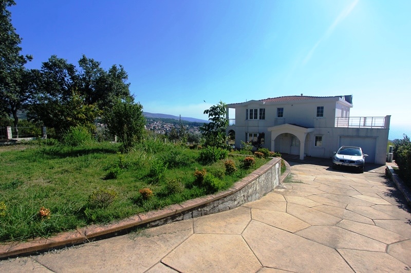 Two-story villa with a garage and green grounds in Dobra Voda, Montenegro: front view and surrounding area.