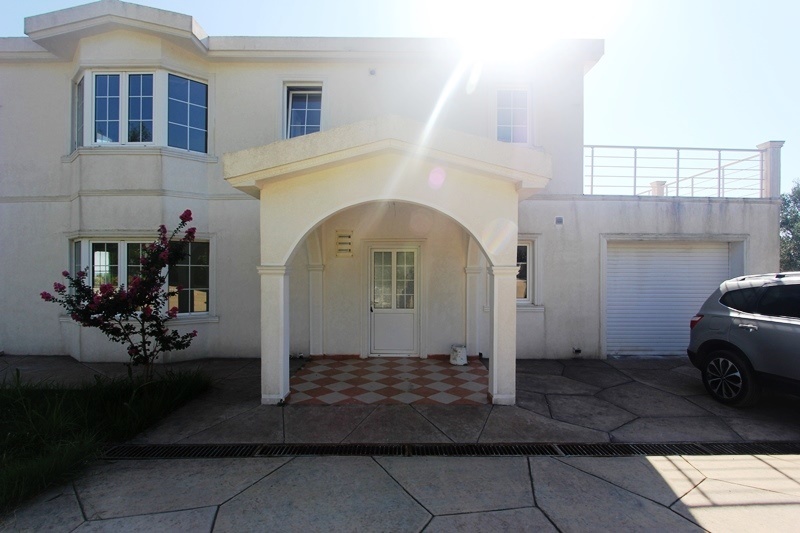 Two-story villa in Dobra Voda, Montenegro: facade with an arched entrance, terrace, garage, and parking space.
