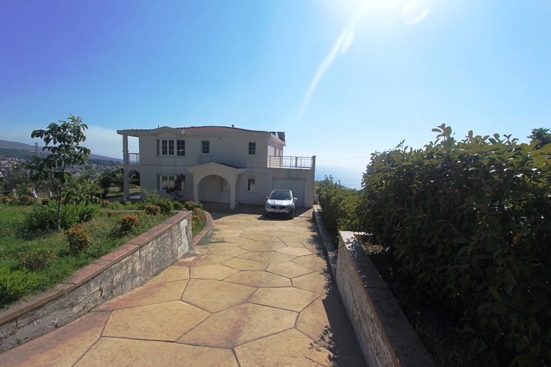 Two-story villa with a garage and terrace in Dobra Voda, Montenegro: front view and stone driveway.