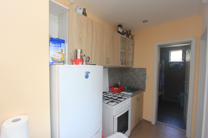Kompakte Küche mit weißem Kühlschrank und Gasherd im Haus, Seoce, Montenegro. Blick auf den Eingang zum Badezimmer.
