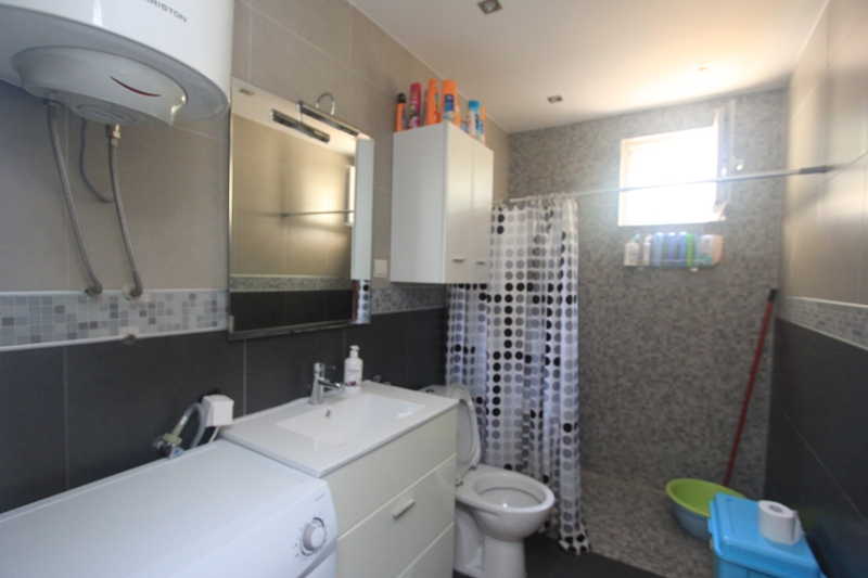 Modernes Badezimmer mit Dusche und Waschmaschine im Haus, Seoce, Montenegro. Fliesenverkleidung, helles Interieur.