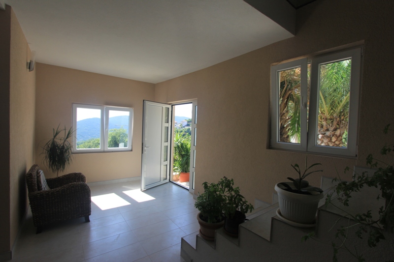 Helles Wohnzimmer in einem Haus in Seoce, Montenegro: geflochtene Sessel, Panoramafenster mit Bergblick und Zugang zur Terrasse.
