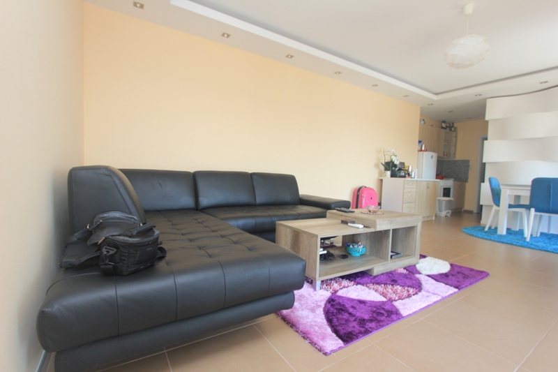 Wohnzimmer mit schwarzem Ledersofa und Essbereich im Haus, Seoce, Montenegro. Modernes Interieur mit buntem Teppich.