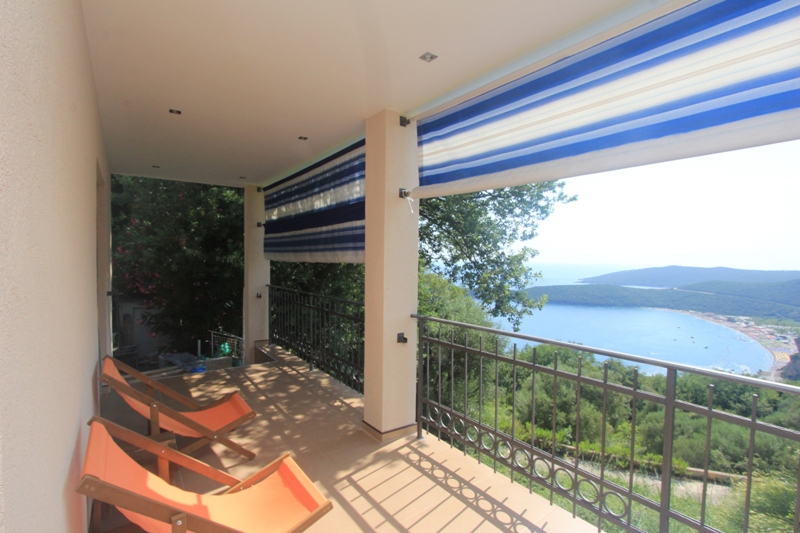 Terrasse mit Liegestühlen und Panoramablick auf das Meer am Haus, Seoce, Montenegro. Gemütlicher Balkon mit Markise und schmiedeeisernem Geländer.