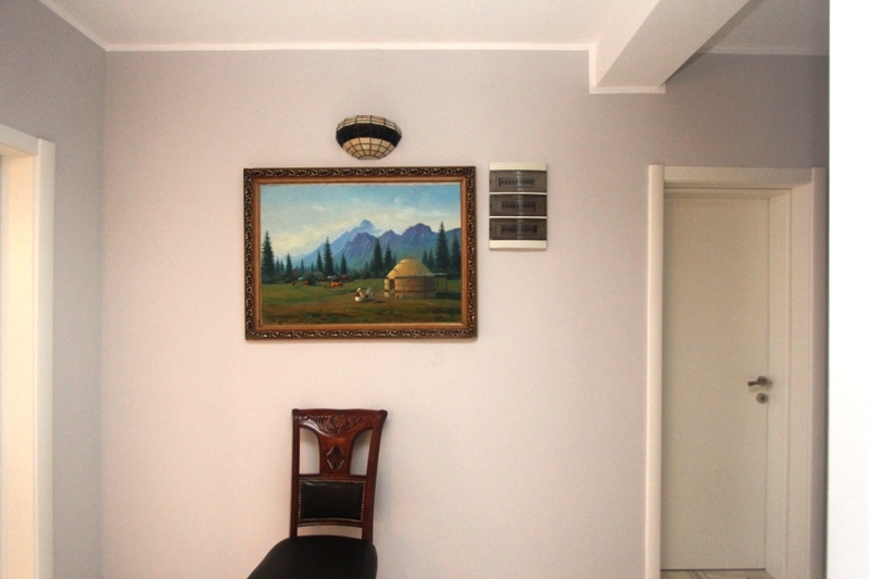Innenraum eines Hauses in Utjeha, Montenegro: helle Wände, ein Landschaftsgemälde, eine Wandleuchte und ein klassischer Stuhl.