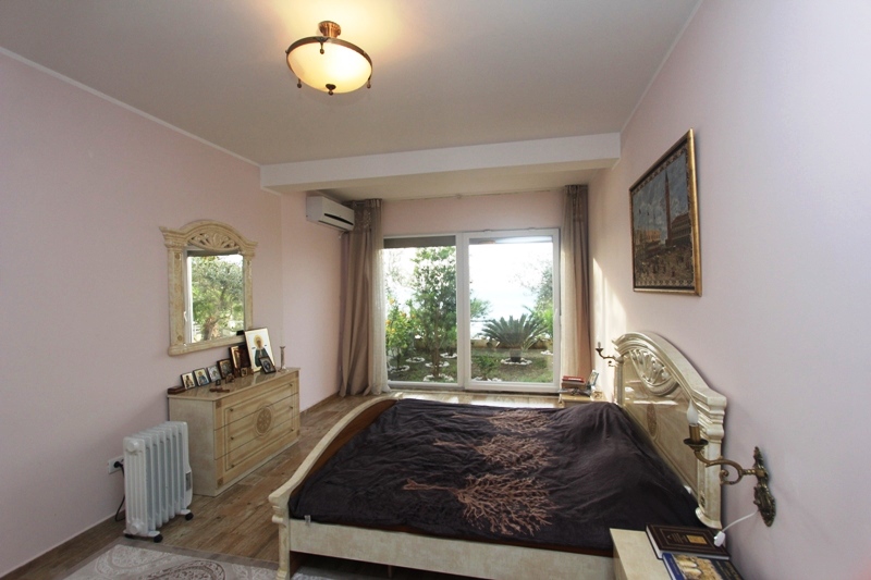 Gemütliches Schlafzimmer mit Doppelbett und Blick auf den Garten in einem Haus zum Verkauf, Utjeha, Montenegro.