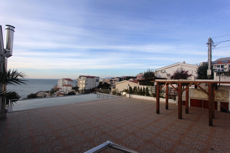 Offene Terrasse mit Pool und Meerblick in einem Haus in Utjeha, Montenegro: Fliesenboden und Holzüberdachung.