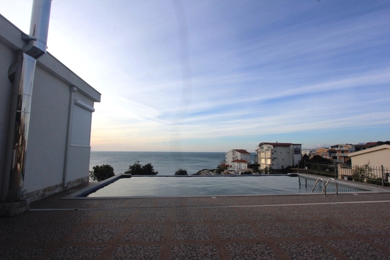 Offener Pool mit Panoramablick auf das Meer am Haus in Utjeha, Montenegro. Terrasse mit Fliesen und moderner Architektur.