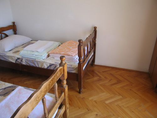 Schlafzimmer mit zwei Holzbetten und Parkettboden in einem Haus zum Verkauf in Bečići, Montenegro