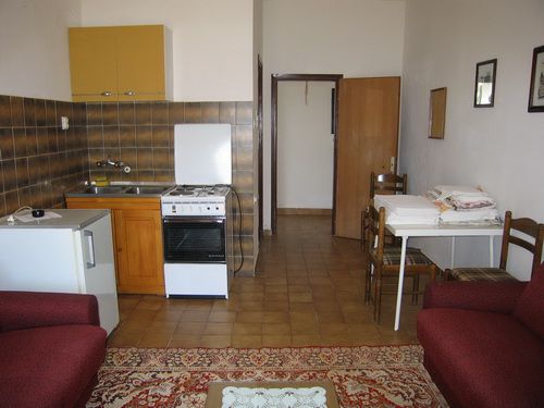 Küche-Wohnzimmer in einem Haus in Bečići, Montenegro: Küchenzeile, Herd, Esstisch und Polstermöbel.