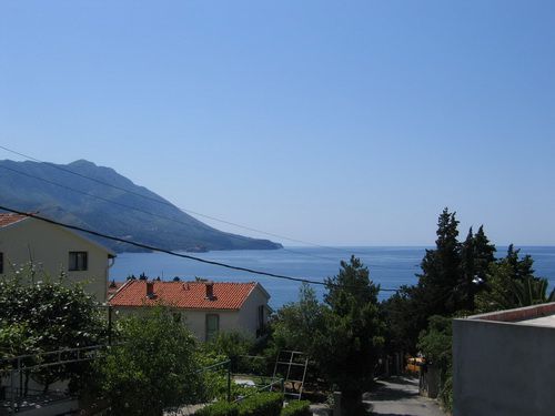 Panoramablick auf das Meer und die Berge vom Haus in Bečići, Montenegro: Ziegeldächer, Grün und Meereslandschaft.