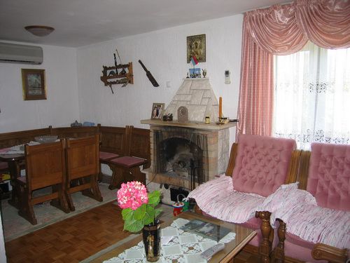 Wohnzimmer mit Kamin, Holzmöbeln und Sitzecke in einem Haus zum Verkauf in Bečići, Montenegro.