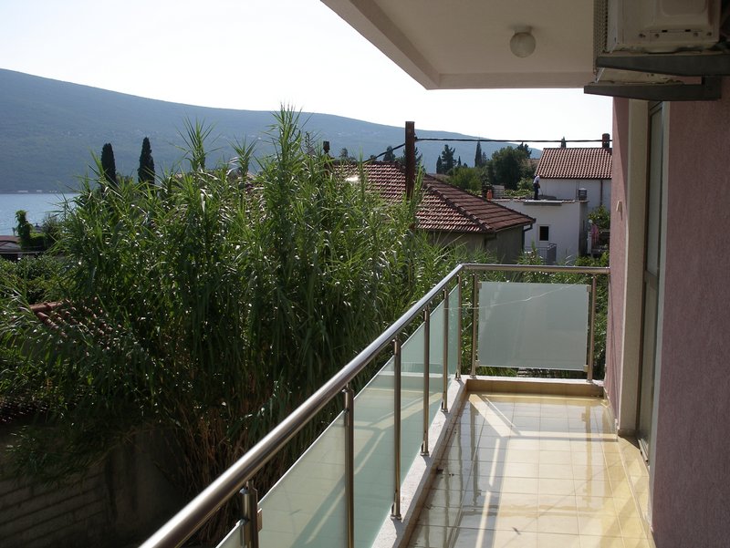 Karoda zeminli ve cam korkuluklu balkon, Baosici, Karadağ’daki dairede, deniz ve dağ manzaralı.