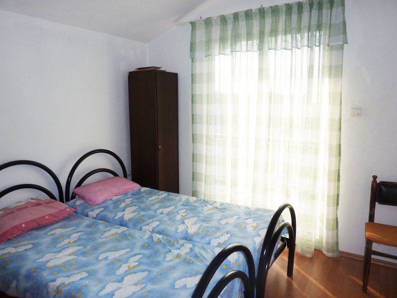 Schlafzimmer mit zwei Betten und Kleiderschrank im Haus, Stadt Dobrye Vody, Montenegro. Heller Raum mit Fenster und Parkett.