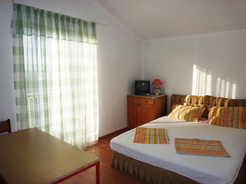 Helles Schlafzimmer mit Doppelbett und Zugang zum Balkon in einem Haus, Dobri Vody, Montenegro.