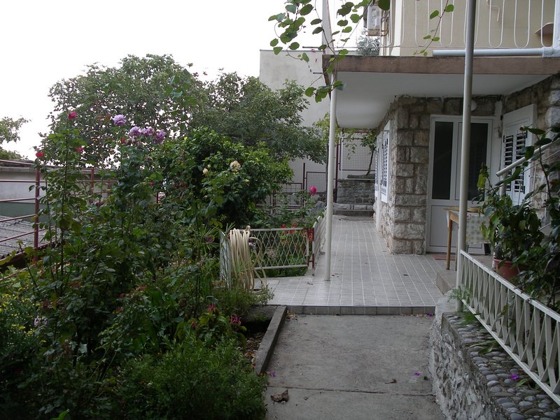 Gemütliche Terrasse und blühender Garten am Haus in Petrovac, Montenegro: Steinverkleidung der Fassade und Blick auf das Grundstück.