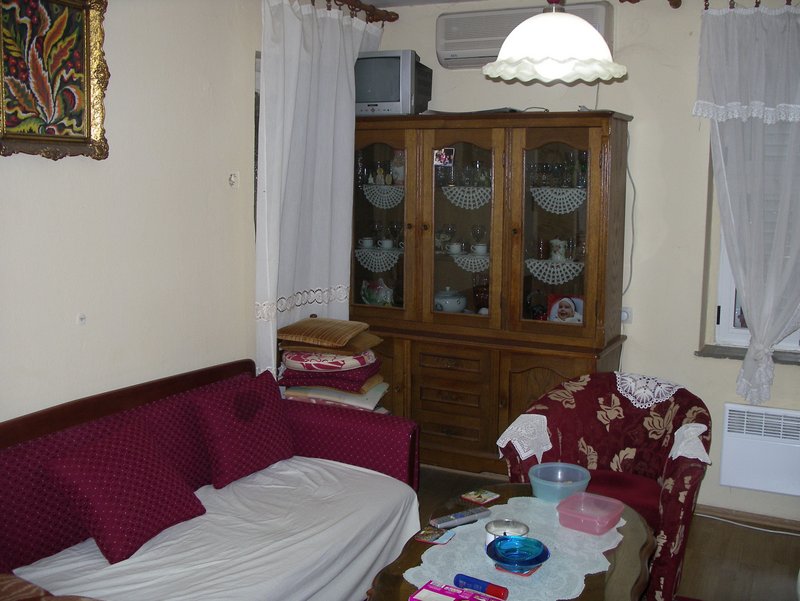 Wohnzimmer in einem Haus in Petrovac, Montenegro: klassischer Holzschrank, weiches Sofa, Sessel und Couchtisch.