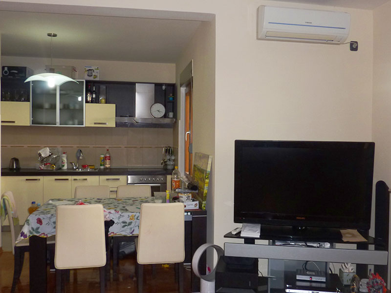 Wohnzimmer mit Küche und Essbereich in der Wohnung, Sveti Stefan, Montenegro: helle Möbel, TV und Klimaanlage.