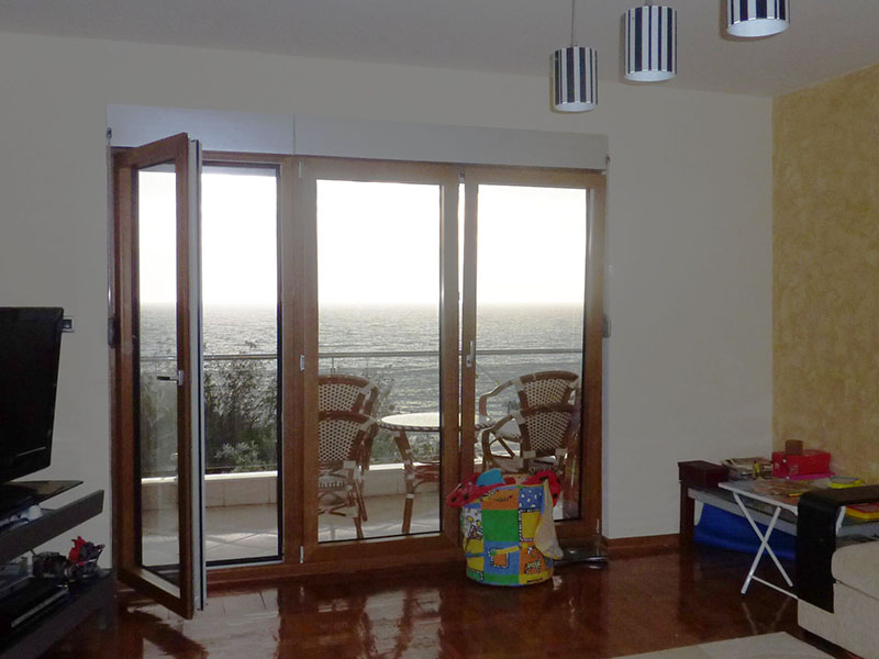 Wohnzimmer in einer Wohnung in Sveti Stefan, Montenegro, mit Panoramablick auf das Meer und Zugang zu einer möblierten Terrasse.