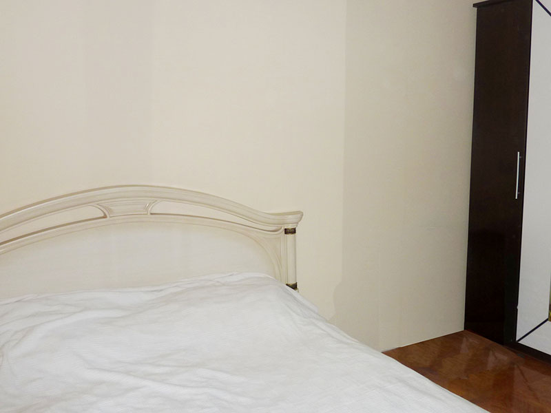 Schlafzimmer in einer Wohnung in Sveti Stefan, Montenegro: Doppelbett mit weißem Kopfteil und Kleiderschrank im Interieur.