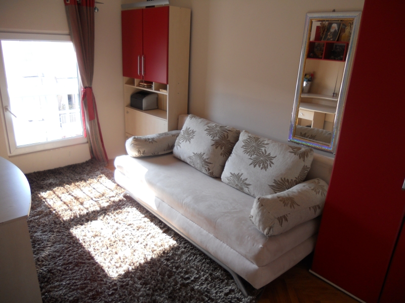 Gemütliches Wohnzimmer mit Sofa, Teppich und Schrank in einer Wohnung zum Verkauf in Budva, Montenegro.