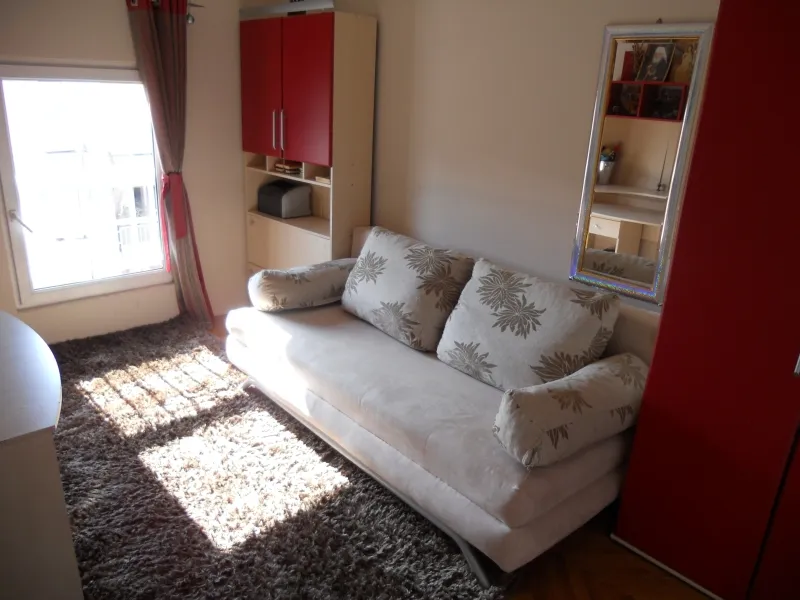 Gemütliches Wohnzimmer mit Sofa, Teppich und Schrank in einer Wohnung zum Verkauf in Budva, Montenegro.