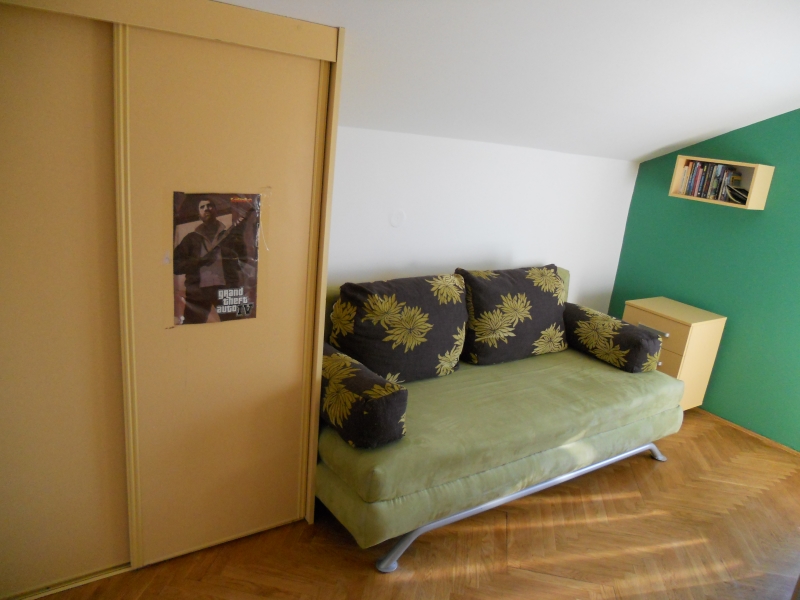 Wohnzimmer in einer Wohnung in Budva, Montenegro: Sofa mit Blumenmuster, Kleiderschrank, Parkett und grüne Akzentwand.