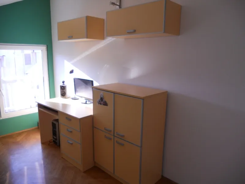 Arbeitsbereich im Schlafzimmer einer Wohnung in Budva, Montenegro: Schreibtisch, Schränke, Computer und Parkettboden.