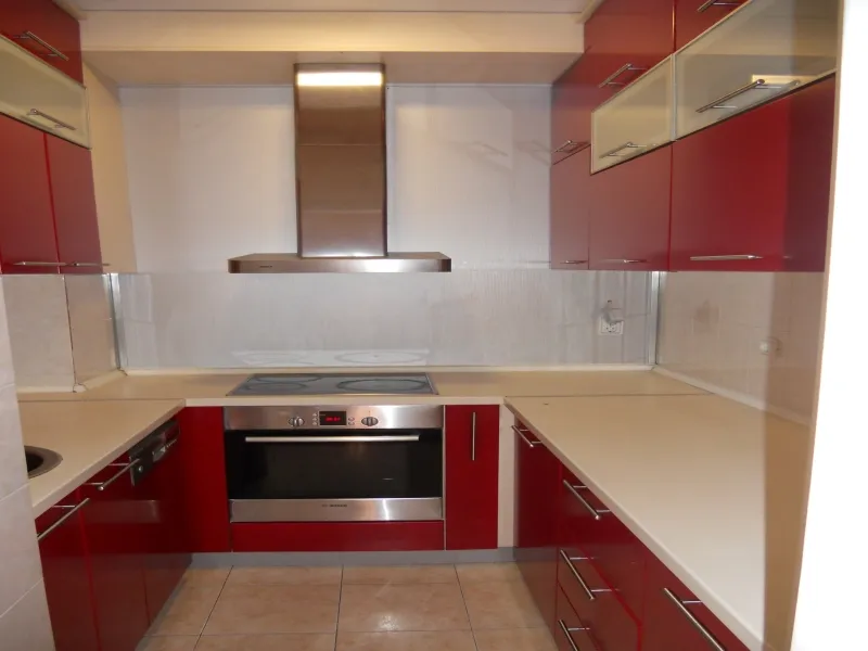 Moderne Küche mit roten Fronten und Einbaugeräten in einer Wohnung zum Verkauf in Budva, Montenegro.