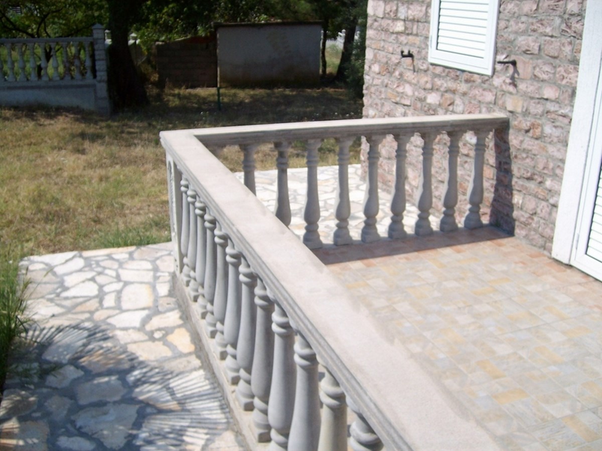 Ein steinrouter Balkon mit Balustraden an der Außenwand eines Hauses.