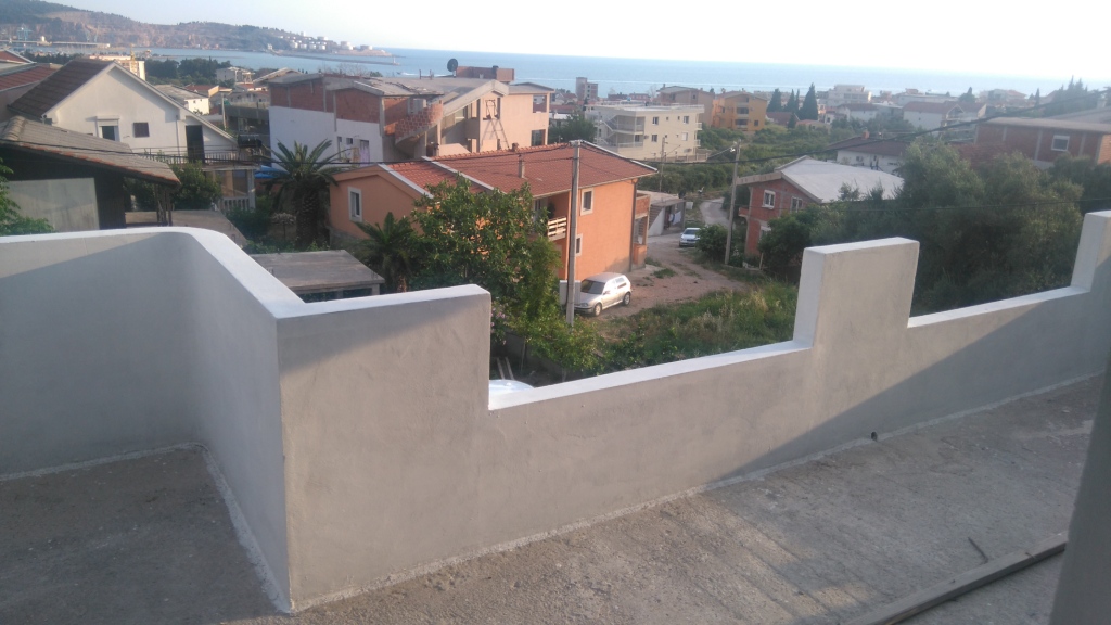 Blick vom offenen Balkon eines Hauses in Šušanj, Montenegro: Panorama auf das Meer, das Wohnviertel und die Berge bei klarem Wetter.