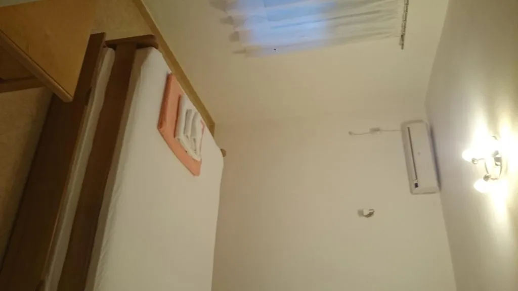 Ein kompaktes Schlafzimmer mit Bett, Klimaanlage und Wandleuchte.