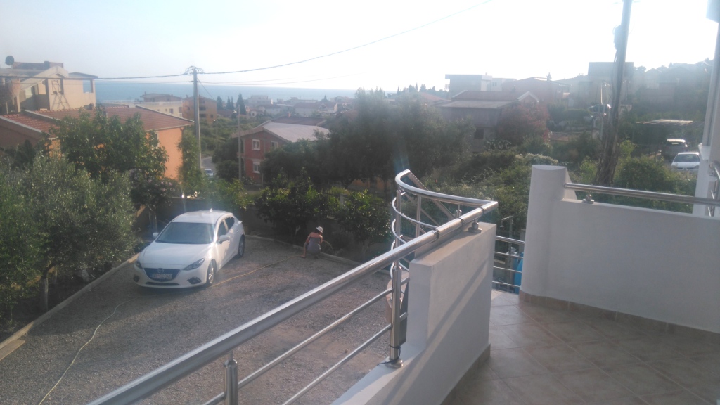 Blick vom Balkon des Hauses in Šušanj, Montenegro: privater Parkplatz, grüner Garten und Panoramablick auf das Meer und die Berge.